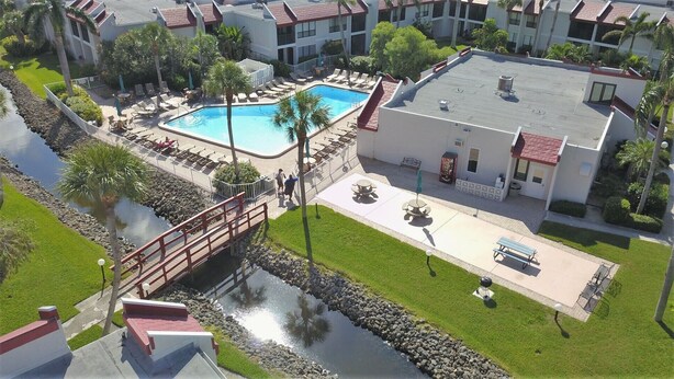 A hotel with a swimming pool, outdoor seating, and a bridge over a water feature. - Runaway Bay (Bradenton Beach)