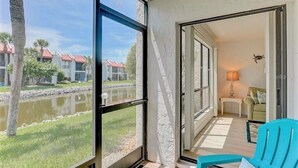 A room with a view of a water body and buildings, a teal chair, and a lamp. - Runaway Bay (Bradenton Beach)