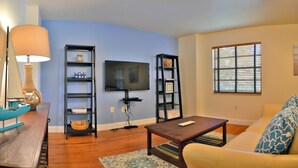 A living room with a TV, two bookshelves, a sofa, and a coffee table. - Desoto (Bradenton)