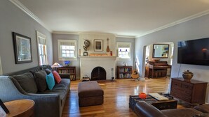 Un salon spacieux doté d’une cheminée, d’un plancher en bois et d’un grand téléviseur.