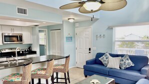 A modern kitchen with a central island, bar stools, a blue sofa, and a glass coffee table. - Seaside Escape (Bradenton Beach)
