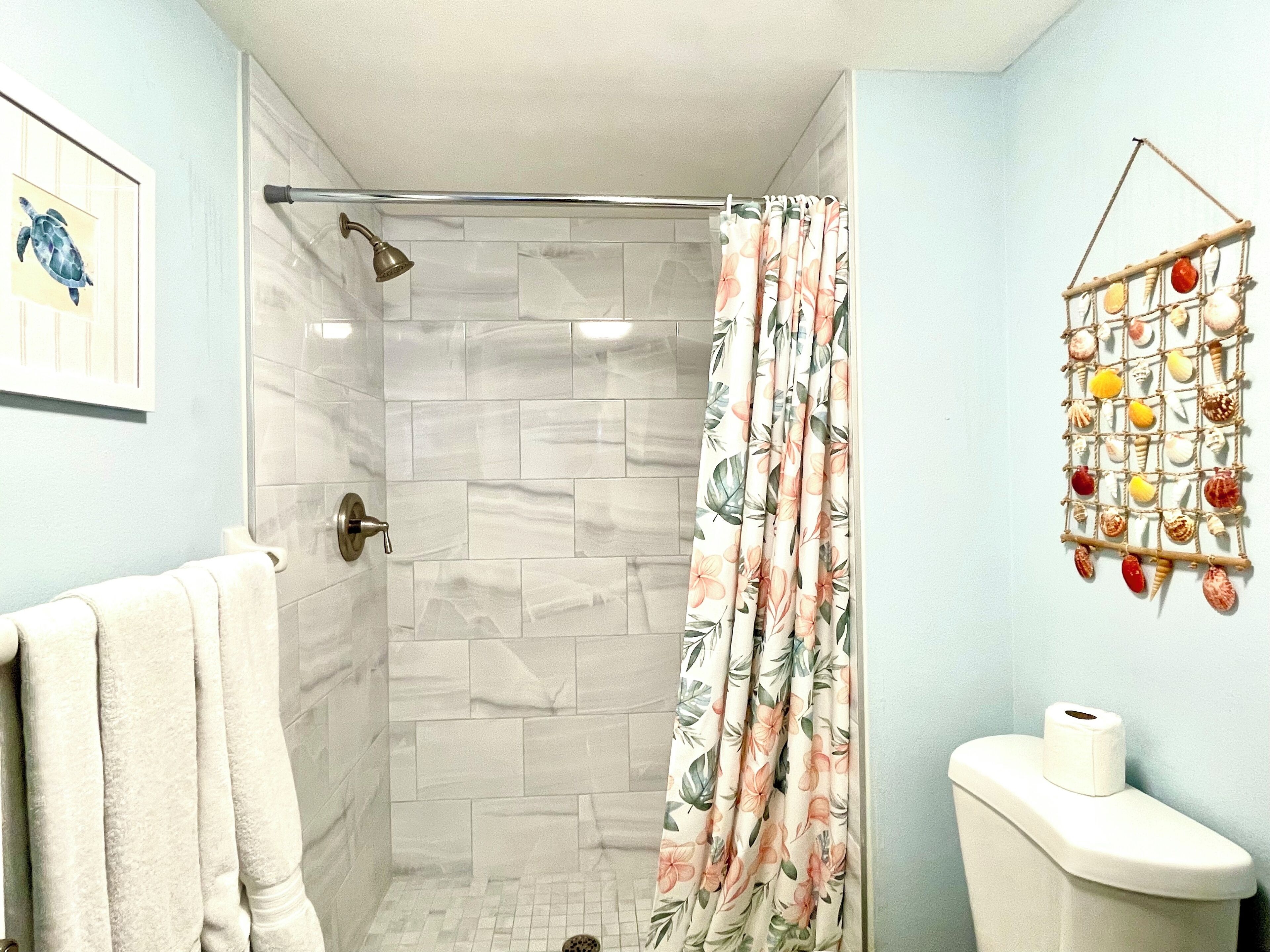 Une salle de bain équipée d’une douche, de toilettes et d’un porte-serviettes.