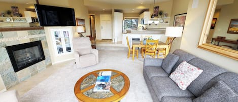 A living room with a fireplace, a sofa, a coffee table, and a TV mounted on the wall.