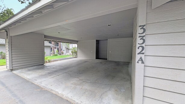 Un garage residenziale con vialetto in cemento e area di parcheggio coperta.