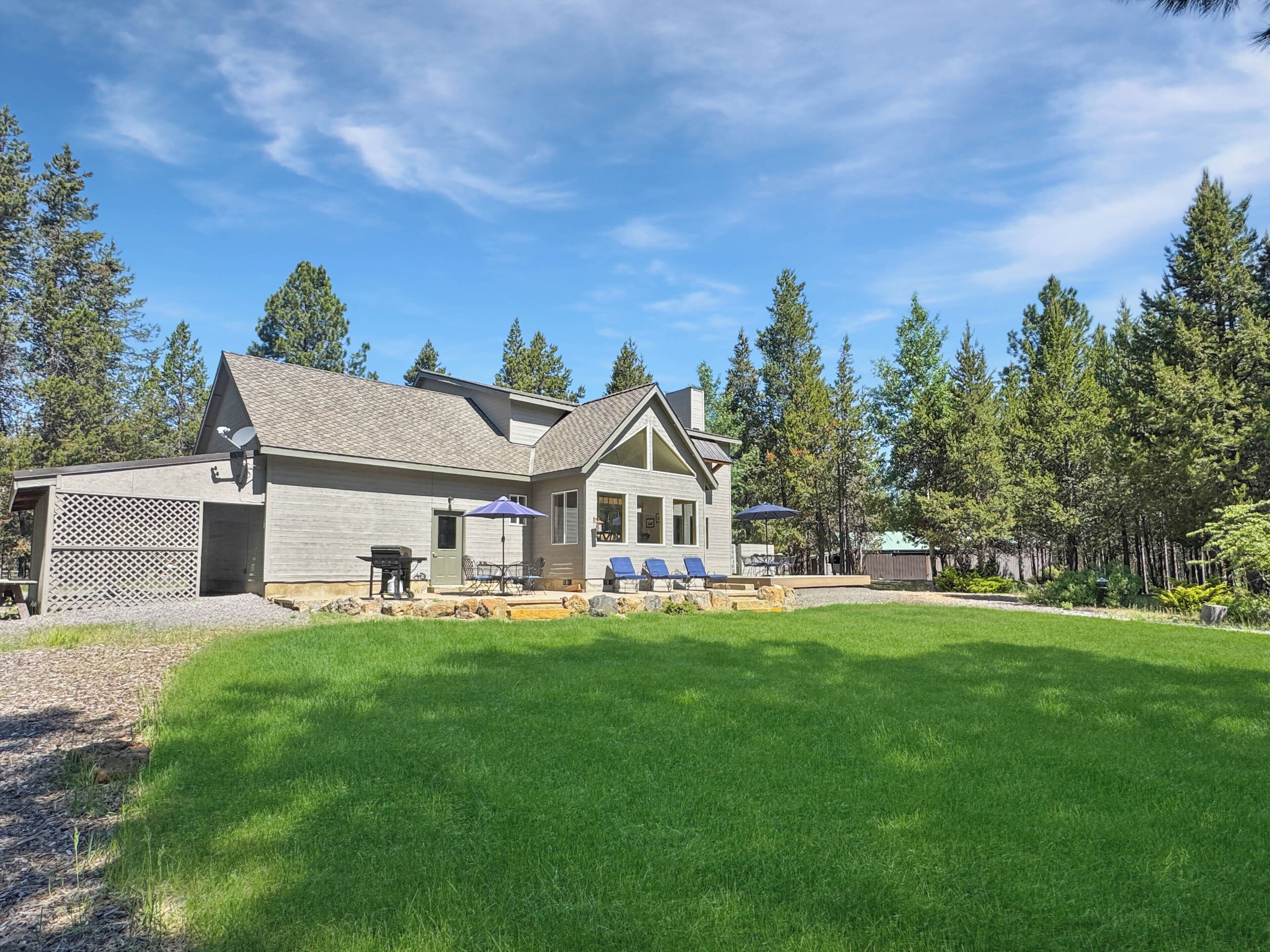 A two-story house with a large front lawn, a patio with outdoor furniture, and a satellite dish.