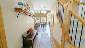 A hallway with a wooden bench, a rug, and a staircase with a wooden railing. - Aspen Place River Access & Ping Pong (Bend)