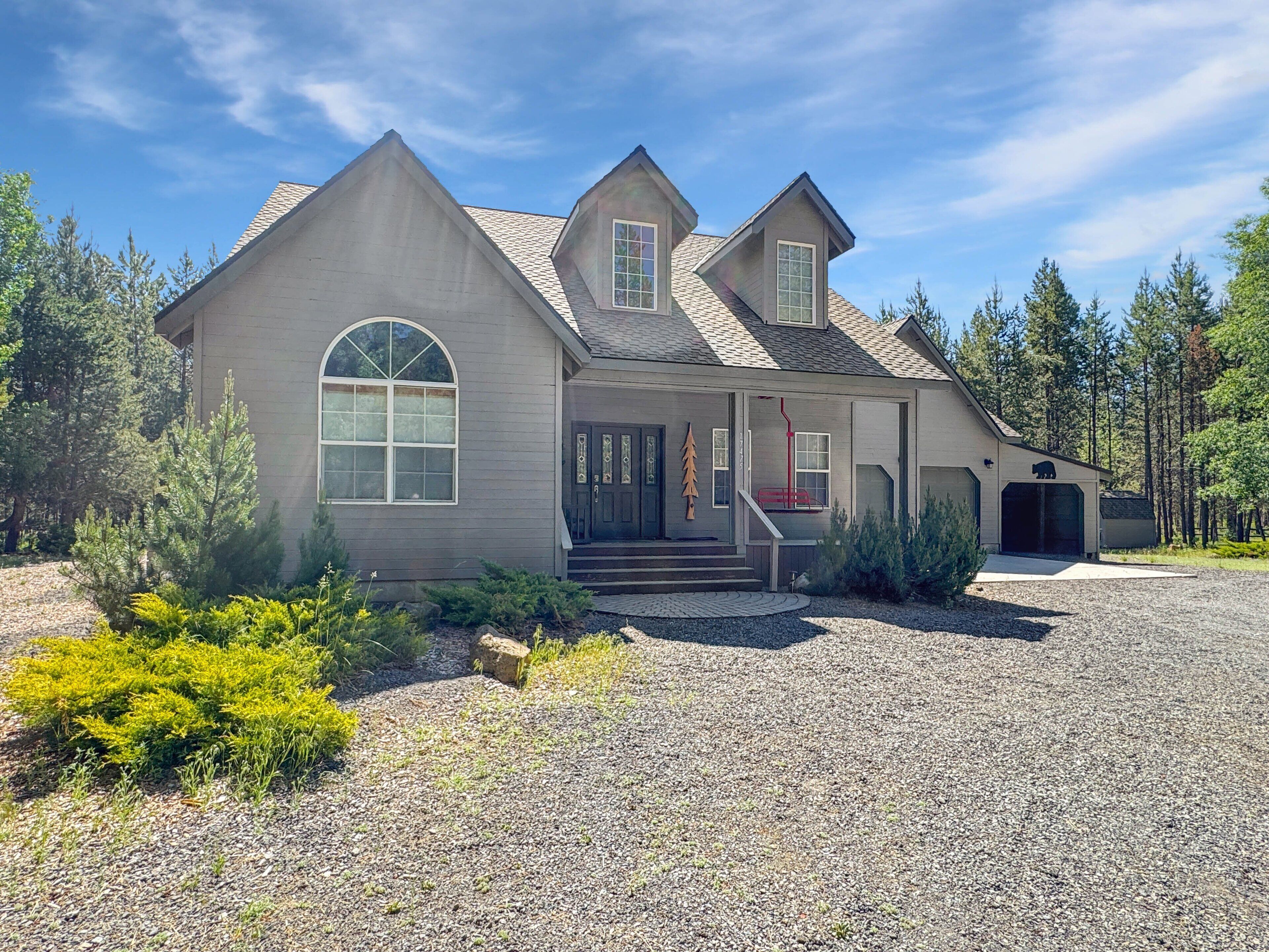 A two-story house with a large front porch, a garage, and a driveway.