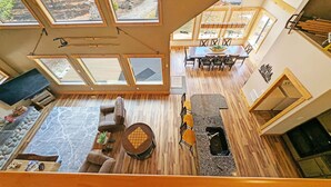 A spacious living area with a fireplace, a dining table, and multiple windows. - Aspen Place River Access & Ping Pong (Bend)