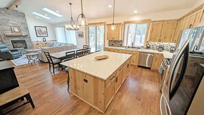 Eine geräumige Küche mit Holzausstattung, einer zentralen Kochinsel und einem Kamin aus Stein.