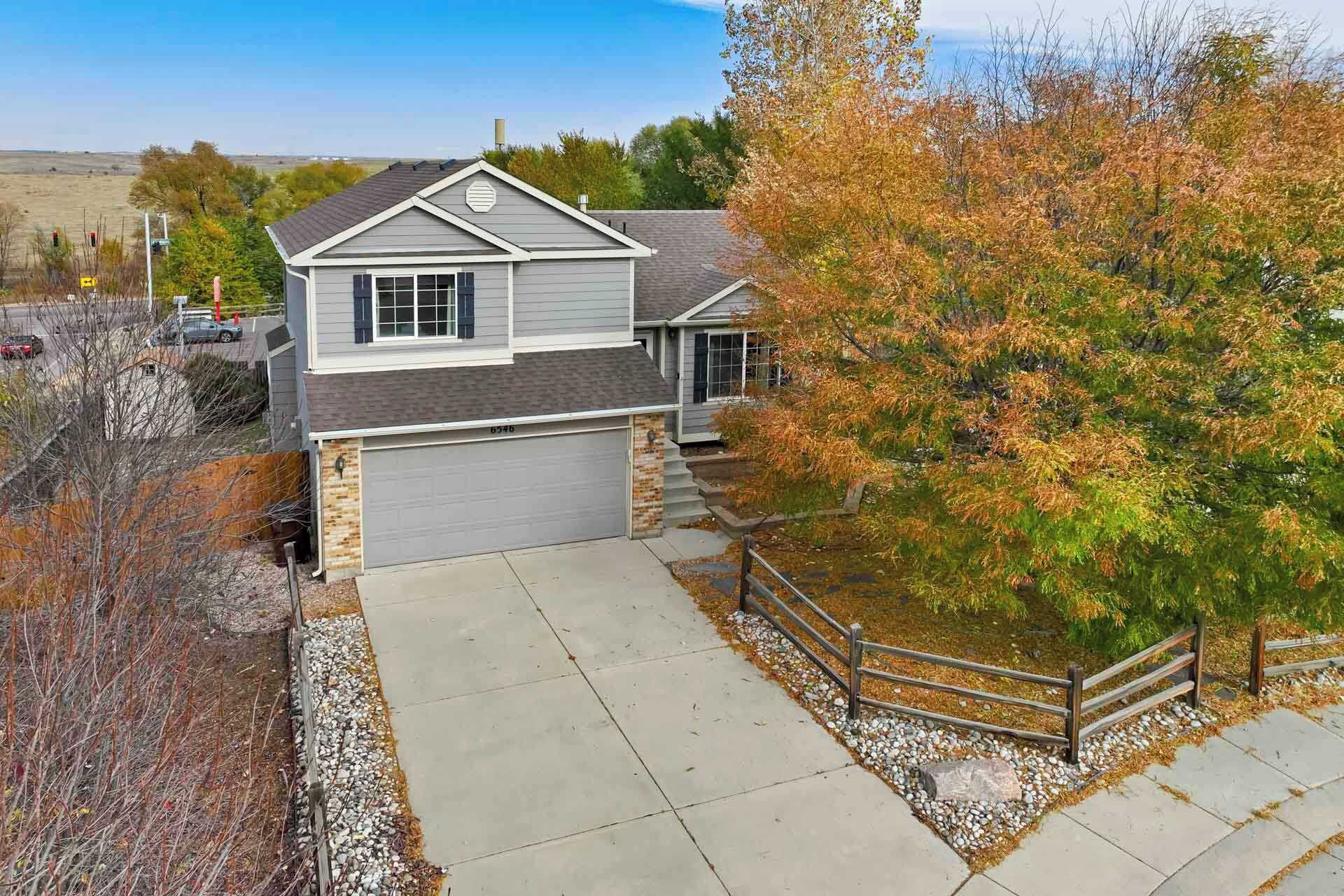 A two-story house with a garage, a driveway, and a wooden fence.