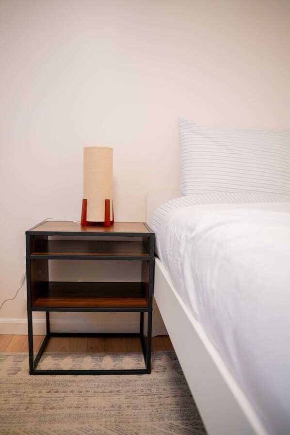 A bed with white bedding, a nightstand with a lamp, and a patterned rug. - Modern 3BR - Rare AC in Seattle - Family-Friendly (Seattle)