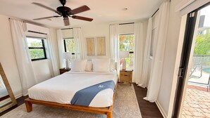 A bedroom with a bed, a ceiling fan, a nightstand with a lamp, and a view of the outdoors through a sliding door. - Waterfront, Pool + South Florida Vibes - Perfect! (Pompano Beach)