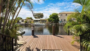 A wooden dock leading to a marina with boats, surrounded by palm trees and buildings. - Waterfront, Pool + South Florida Vibes - Perfect! (Pompano Beach)
