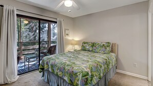A bedroom with a bed, a ceiling fan, a window with curtains, and a view of a deck. - 10D Amelia Landings (Fernandina Beach)