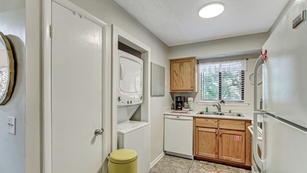 A compact kitchen with a washing machine, a coffee maker, and wooden cabinets. - 10D Amelia Landings (Fernandina Beach)