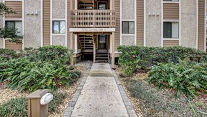 A multi-story building with a central entrance, a sign reading "VILLAS 10A-10F", and a pathway leading to the entrance. - 10D Amelia Landings (Fernandina Beach)