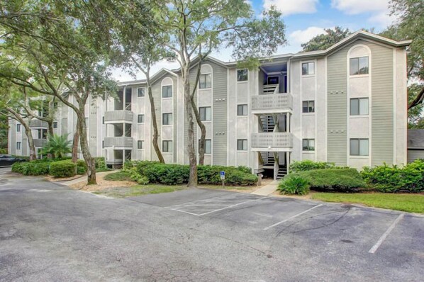 A multi-story residential building with a central courtyard, balconies, and a parking area. - 10D Amelia Landings (Fernandina Beach)
