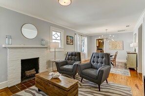 A living room with a fireplace, two grey armchairs, a wooden coffee table, and a zebra-patterned rug. - 114 S 6th Street (Fernandina Beach)