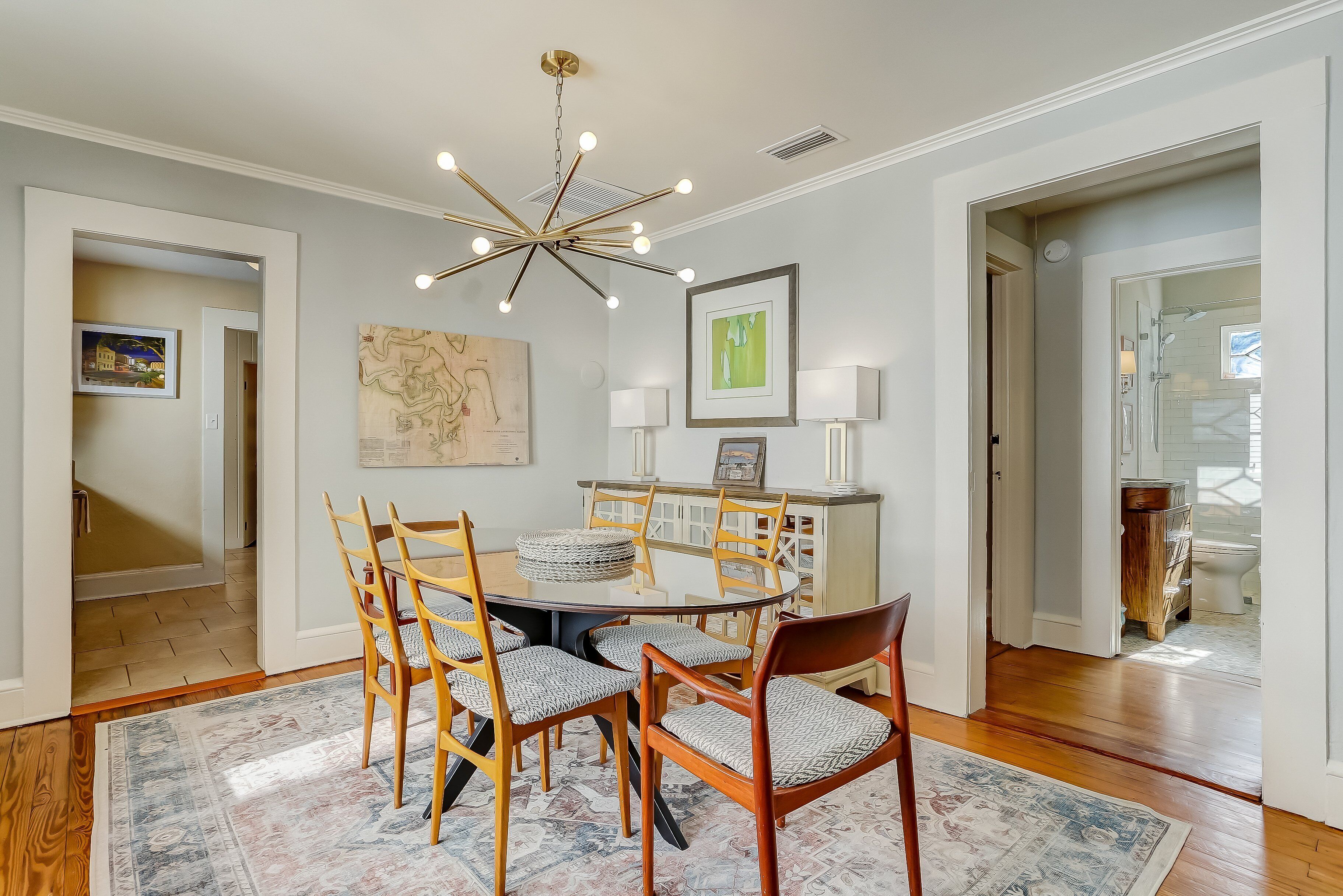 A dining area with a round table, wooden chairs, and a patterned rug.