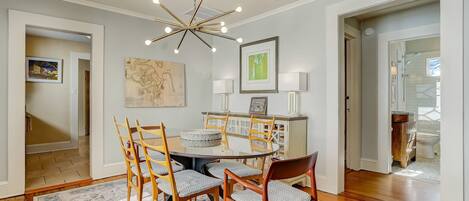 A dining area with a round table, wooden chairs, and a patterned rug.