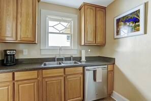 A kitchen with wooden cabinets, a double sink, and a coffee maker. - 114 S 6th Street (Fernandina Beach)