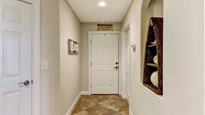 A hallway with a white door, a sign above the door, and a shelf with a decorative item. - 1 Block From the Beach, Next to Ft Clinch State Park and 2 Miles From Historic Centre Street (Fernandina Beach)