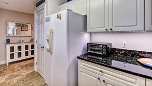 A kitchen with white cabinets, a refrigerator, a toaster oven, and a countertop. - 1 Block From the Beach, Next to Ft Clinch State Park and 2 Miles From Historic Centre Street (Fernandina Beach)