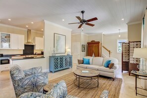 A spacious living room with a sofa, patterned armchairs, a coffee table, and a dining area with cabinets and a kitchen in the background. - 1016 San Fernando Street (Fernandina Beach)