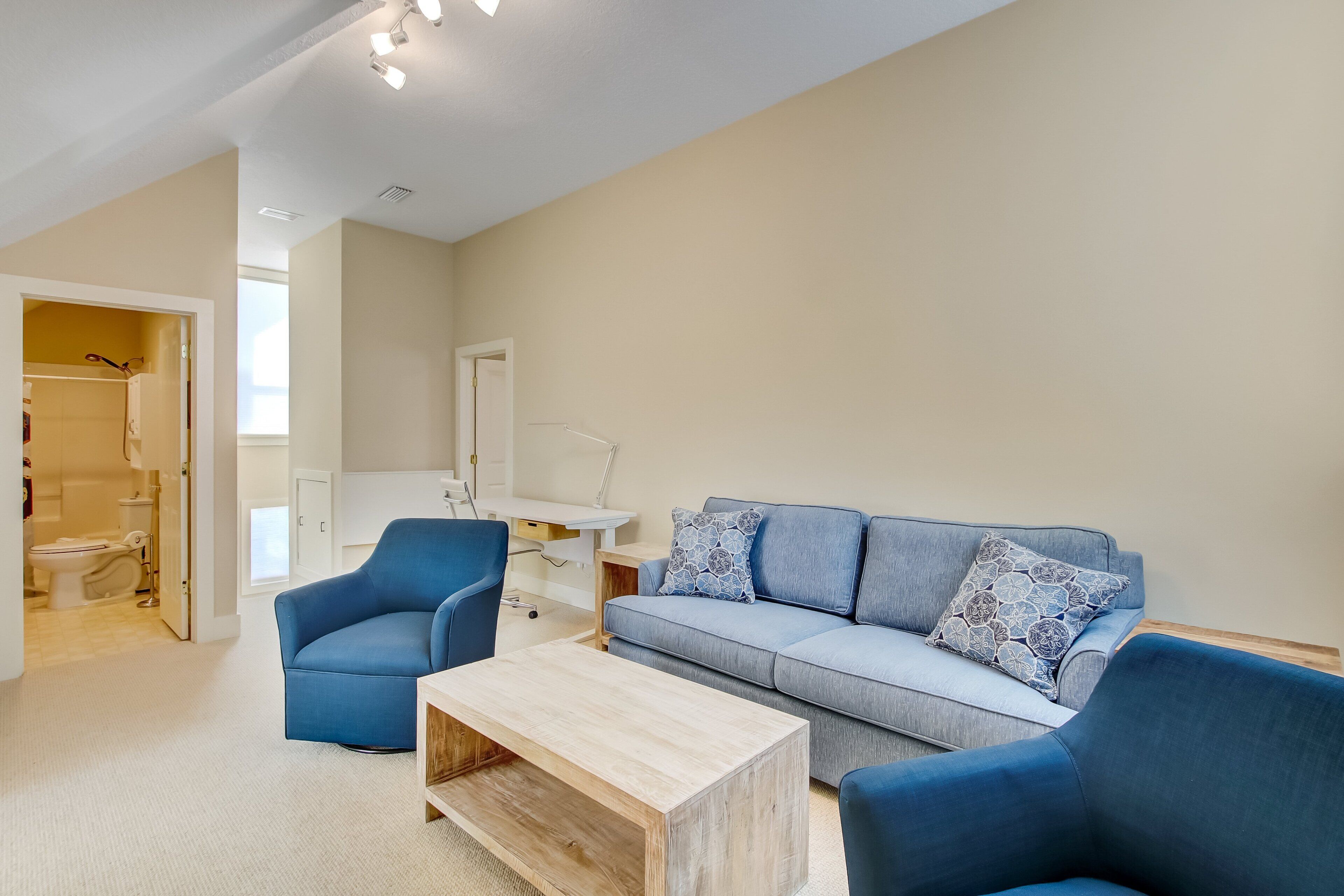 A modern living room with a sofa, chairs, a coffee table, and a desk.
