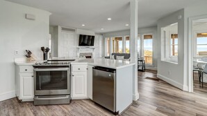 A modern kitchen with white cabinetry, stainless steel appliances, and a large island. - 1650 N Fletcher Ave (Fernandina Beach)