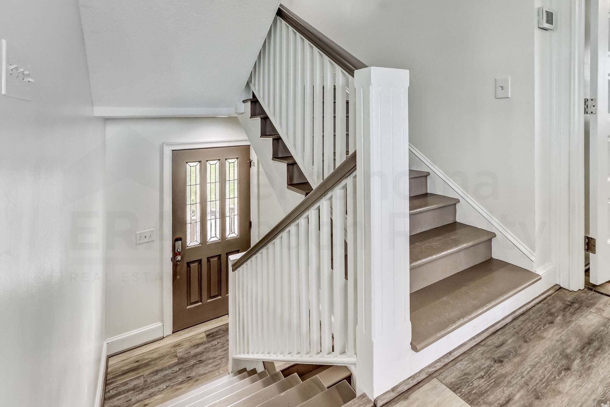 A staircase with white railings and wooden steps leading to a door with a window.