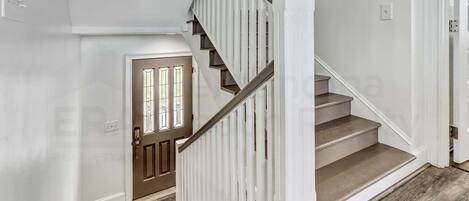 A staircase with white railings and wooden steps leading to a door with a window.
