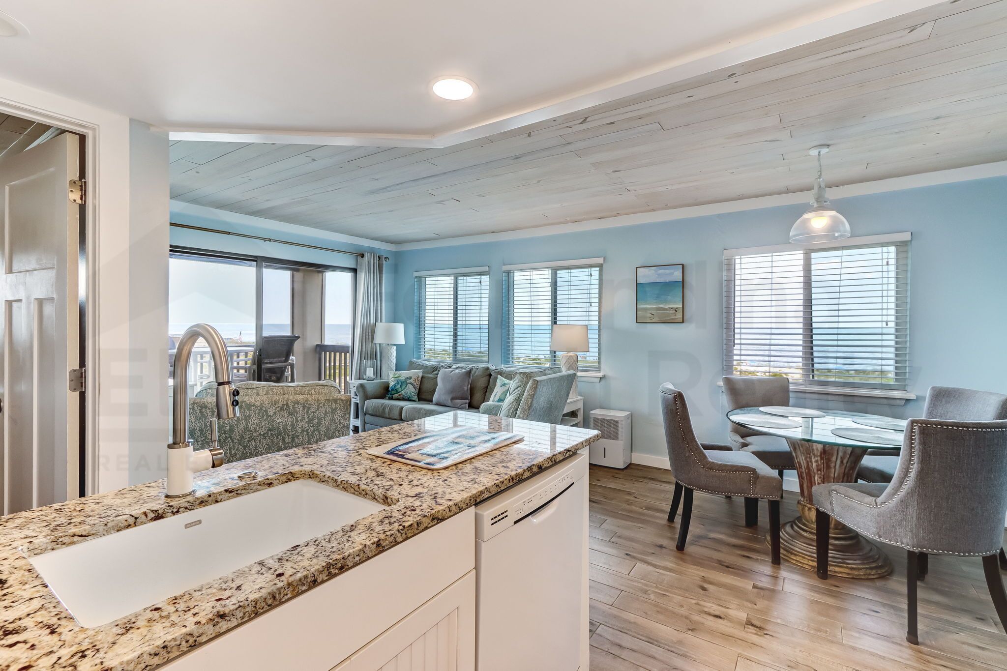 A modern kitchen with granite countertops, a built-in dishwasher, and a dining area with a round table and chairs.