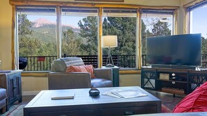 A living room with a large window, a television, and a sign reading "WELCOME TO GOD'S COUNTRY." - 181 Horseshoe (Divide)