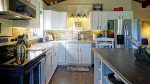 A modern kitchen with white cabinets, stainless steel appliances, and a wooden ceiling. - 181 Horseshoe (Divide)