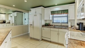 A modern kitchen with white cabinets, a built-in dishwasher, a stove, and a microwave. - 446 Amelia By The Sea (Fernandina Beach)