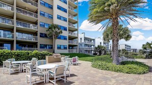 A hotel courtyard with outdoor seating, palm trees, and a multi-story building with balconies. - 446 Amelia By The Sea (Fernandina Beach)