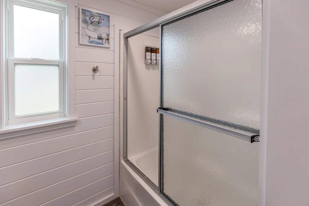 Un baño con cabina de ducha, ventana y armario de medicinas empotrado.