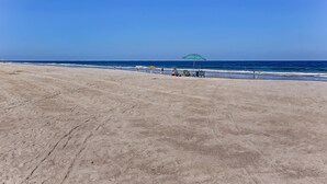 A beach with a clear sky, a few umbrellas, and a few people. - 210 Oceans of Amelia (Fernandina Beach)