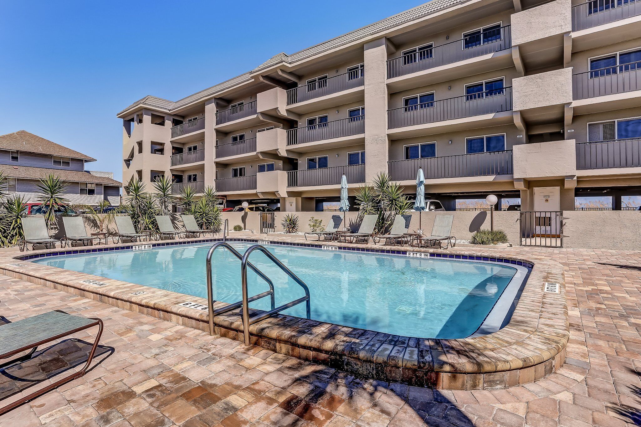 Un hôtel doté d’une piscine, de chaises longues et d’un immeuble à plusieurs étages avec des balcons.