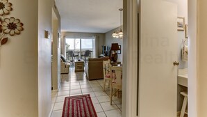 A spacious living room with a sofa, a dining table, and a red rug. - 208 Sand Dollar (Fernandina Beach)