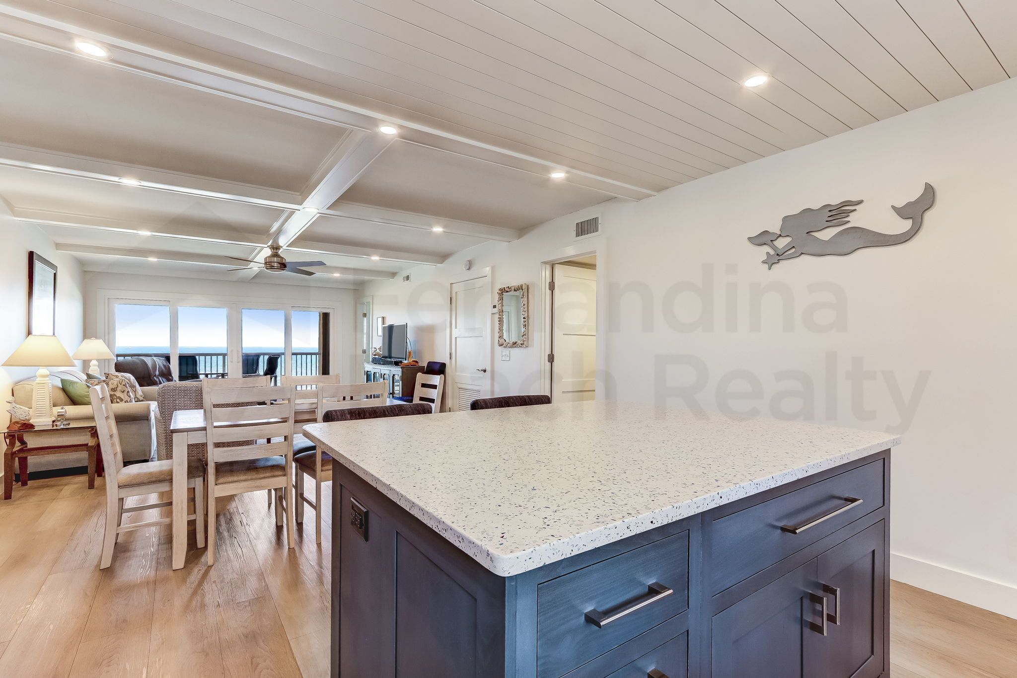 A spacious living area with a kitchen island, wooden furniture, and a ceiling fan.