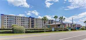 Um hotel com vários andares e design moderno, com varandas em cada pavimento e um pátio central com palmeiras.