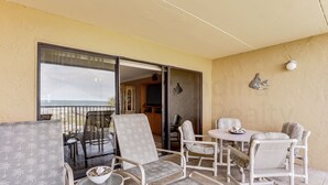 A balcony with wicker furniture, a dining table, and a view of the ocean. - 204 Atlantis (Fernandina Beach)