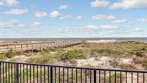 A wooden boardwalk leading to a beach with a clear sky and clouds. - 204 Atlantis (Fernandina Beach)