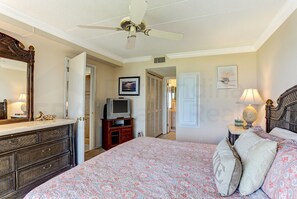 A bedroom with a bed, dresser, television, and ceiling fan. - 204 Atlantis (Fernandina Beach)