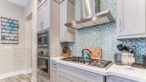 Una cocina moderna con electrodomésticos de acero inoxidable, estufa a gas y salpicadero de azulejos.
