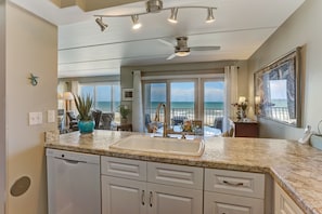 A kitchen with a large island, a dishwasher, and a view of the ocean. - 203 Oceans of Amelia (Fernandina Beach)