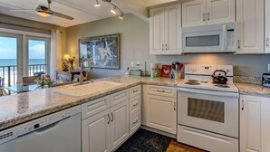 Une cuisine moderne avec des armoires blanches, un four à micro-ondes encastré et une cuisinière.