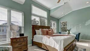 Un dormitorio con una cama grande, un aparador, una silla y una ventana con persianas.